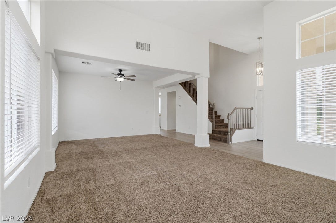 1891 Eagle Flight Lane, Henderson, NV 89012 High ceilings and tall windows frame this light-filled main living space with neutral carpet.