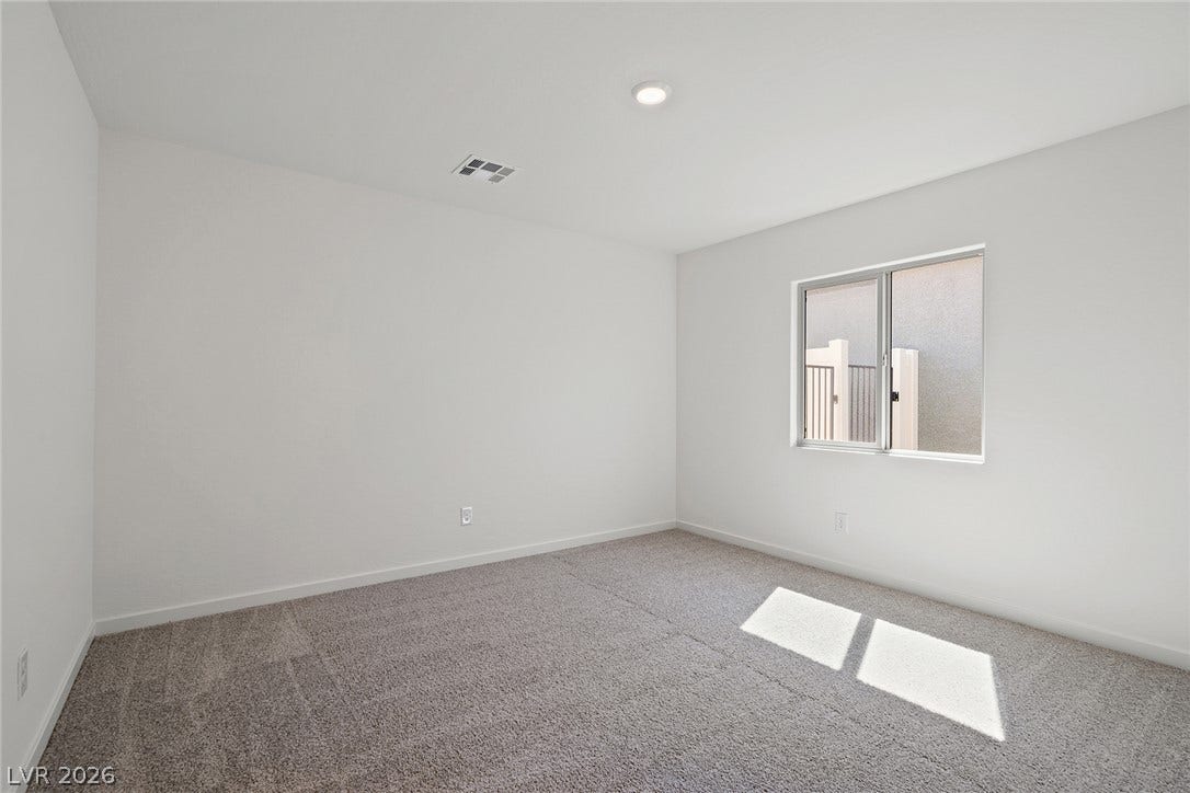 6760 Violet Cascade Avenue, Las Vegas, NV 89156 A single sliding window invites natural light across the carpeted floor of this bedroom.