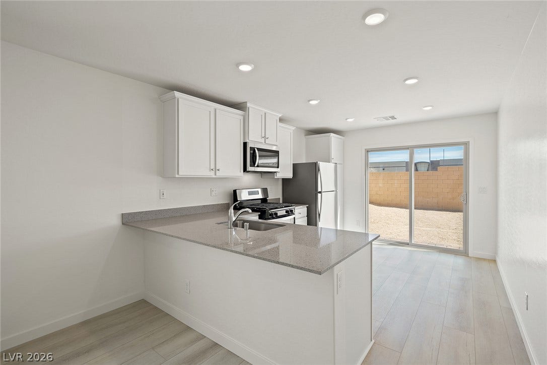 6760 Violet Cascade Avenue, Las Vegas, NV 89156 Smooth countertops and crisp cabinetry anchor this streamlined kitchen opening directly to the yard.