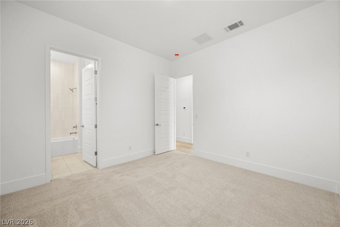 12428 Breezy Bluff Avenue, Las Vegas, NV 89138 Crisp white walls and plush carpeting define this serene guest suite with an attached bath.