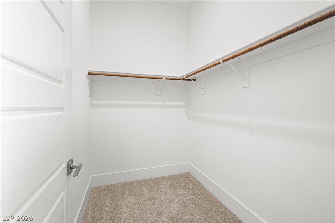 12428 Breezy Bluff Avenue, Las Vegas, NV 89138 A spacious walk-in closet includes built-in shelving, hanging rods, and soft carpeting.