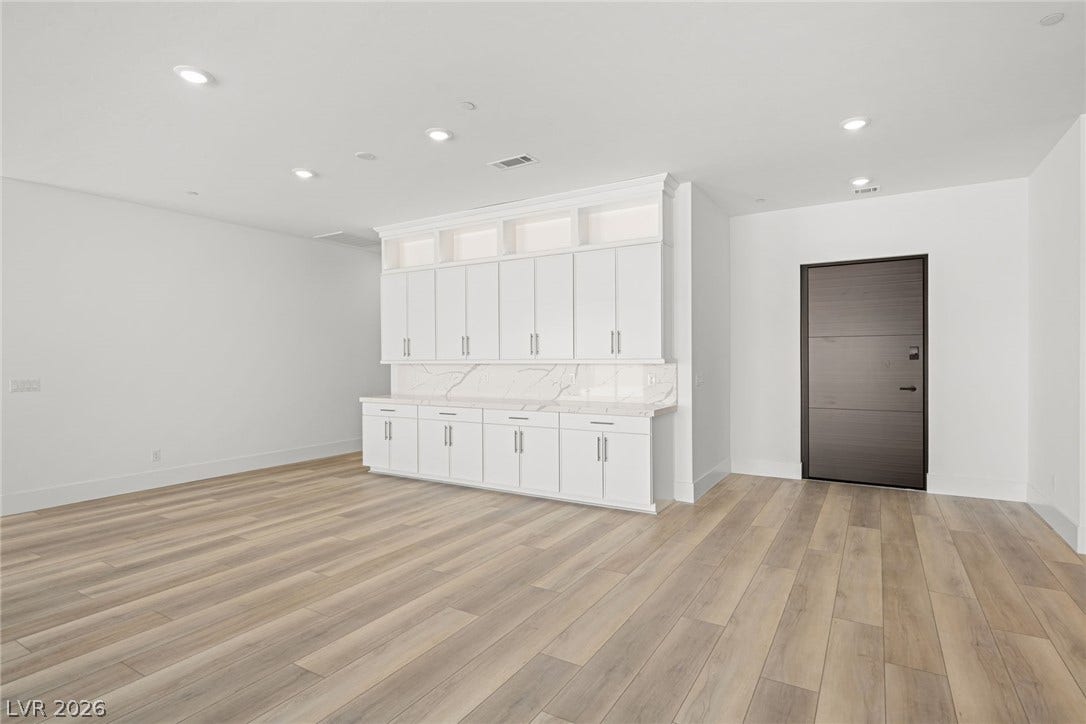12428 Breezy Bluff Avenue, Las Vegas, NV 89138 Rich wood-look flooring and custom built-in cabinetry define this versatile open interior space.