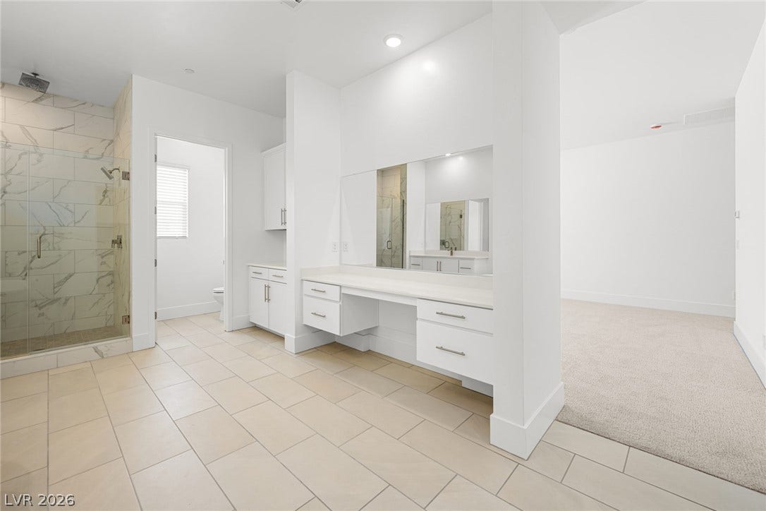 12428 Breezy Bluff Avenue, Las Vegas, NV 89138 A spacious vanity area with built-in cabinetry connects seamlessly to the carpeted bedroom.