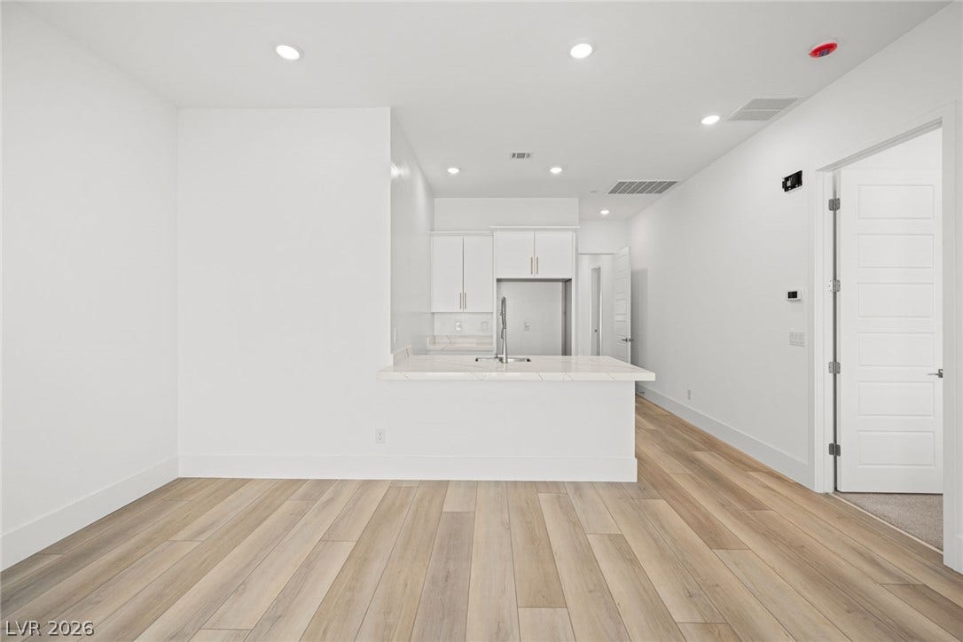 12428 Breezy Bluff Avenue, Las Vegas, NV 89138 Recessed lighting and light-toned wood floors define this streamlined, open living area and kitchen setup.