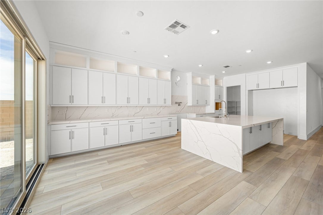 12428 Breezy Bluff Avenue, Las Vegas, NV 89138 A spacious culinary space highlights expansive stone countertops alongside sleek modern cabinetry.
