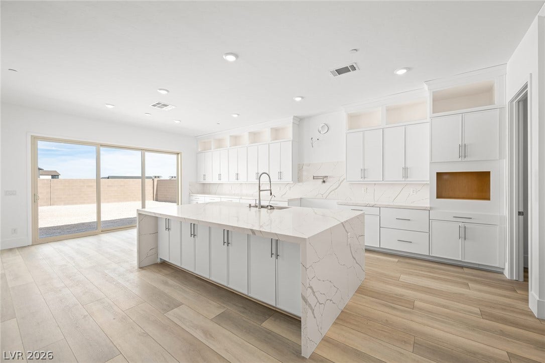 12428 Breezy Bluff Avenue, Las Vegas, NV 89138 An airy culinary space features a massive waterfall island and sleek stone backsplashes.