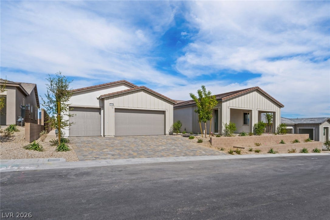 12428 Breezy Bluff Avenue, Las Vegas, NV 89138 Board and batten siding meets a spacious paver driveway under clear desert skies.