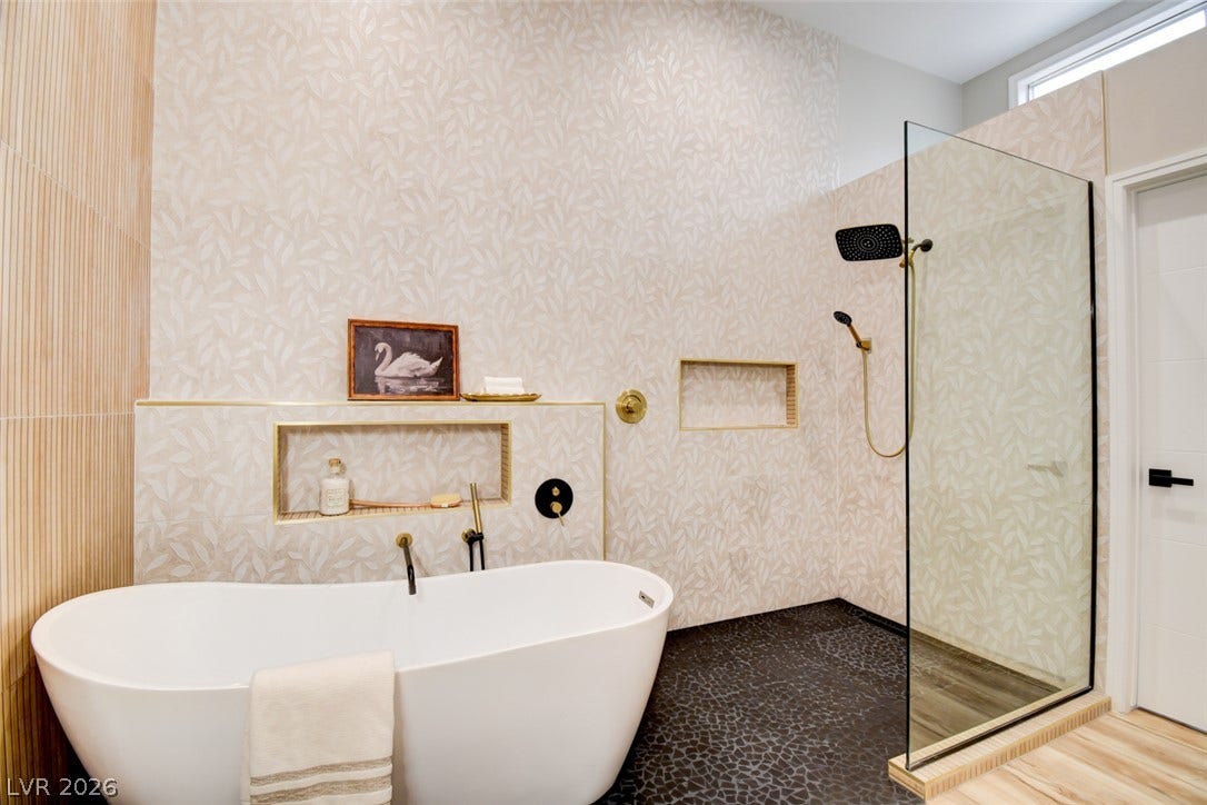2837 Billy Casper Drive, Las Vegas, NV 89134 Elegant freestanding soaking tub sits beside a glass-enclosed shower with custom patterned tile walls.