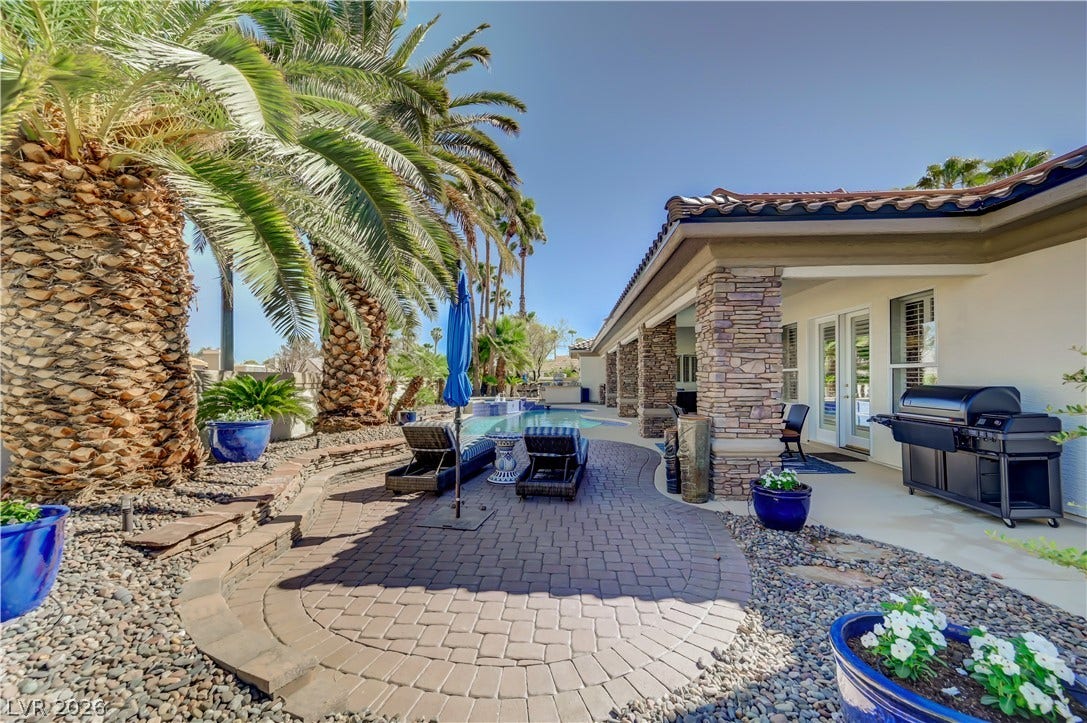 2030 Marina Bay Court, Las Vegas, NV 89117 A spacious stone-accented patio connects the house to a private pool area framed by palms.