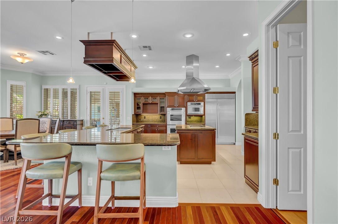 2030 Marina Bay Court, Las Vegas, NV 89117 Rich hardwood floors meet light tile in this open-concept kitchen with a breakfast bar.
