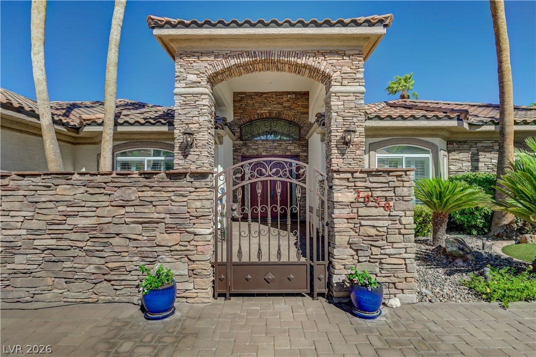 2030 Marina Bay Court, Las Vegas, NV 89117 A secure wrought iron gate opens to a private stone-walled courtyard entry.