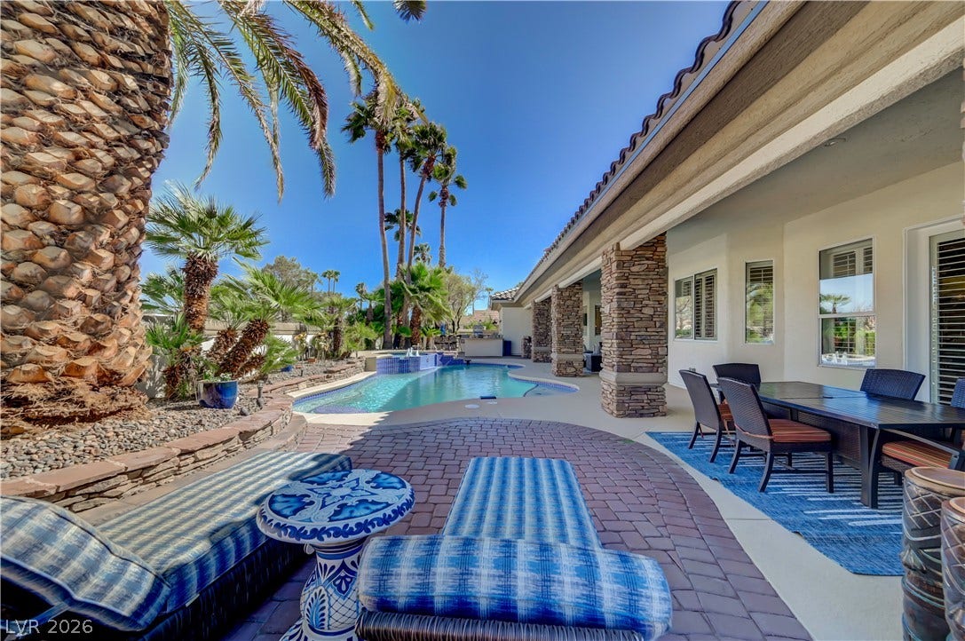 2030 Marina Bay Court, Las Vegas, NV 89117 An inviting backyard oasis showcases a sparkling pool flanked by stone columns and palm trees.