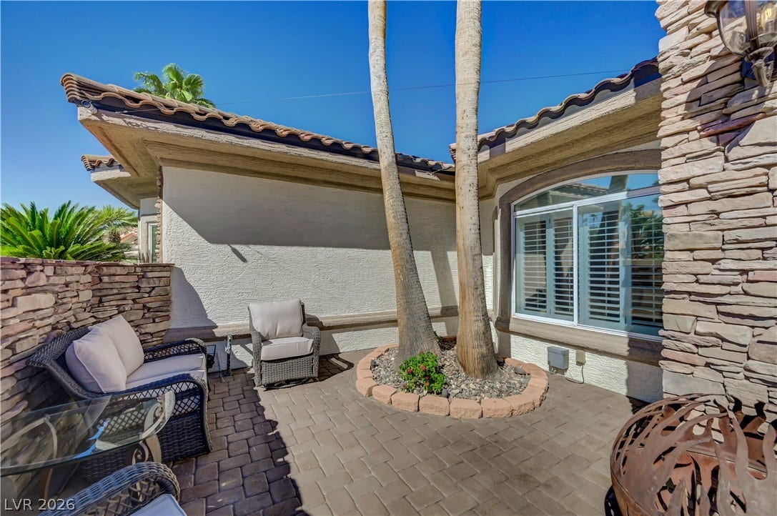 2030 Marina Bay Court, Las Vegas, NV 89117 An inviting stone-paved courtyard is framed by textured masonry walls and mature palm trees.