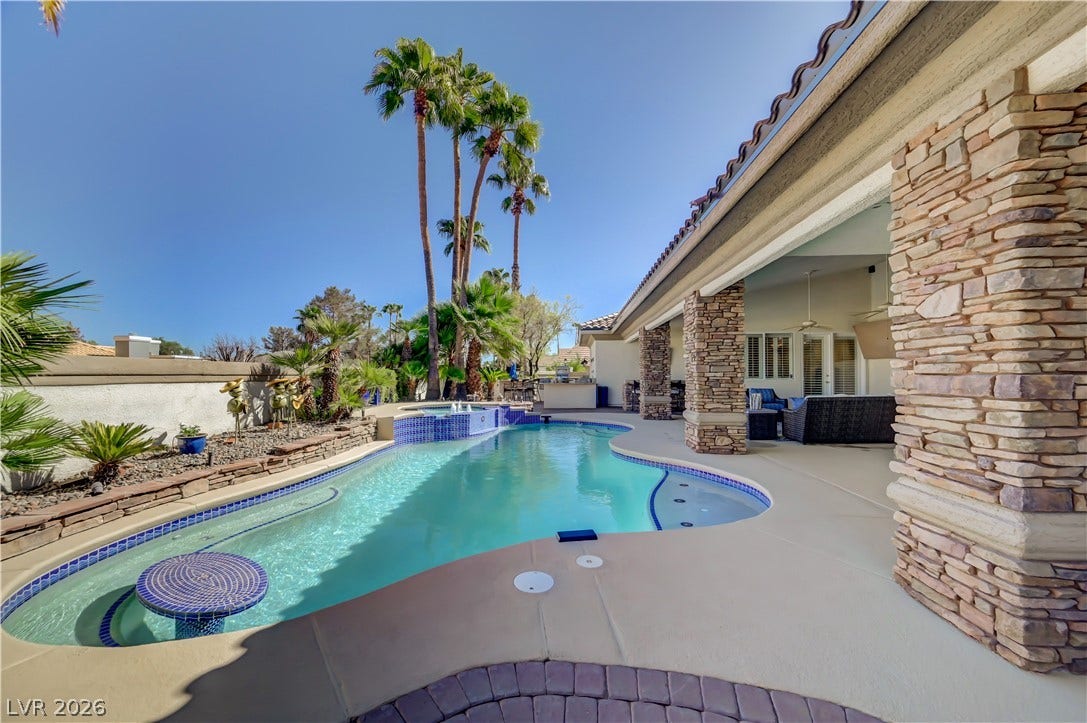 2030 Marina Bay Court, Las Vegas, NV 89117 An inviting backyard oasis showcases a sparkling pool flanked by stone pillars and towering palms.