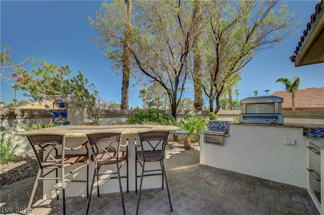 2030 Marina Bay Court, Las Vegas, NV 89117 An inviting outdoor kitchen area on a paver patio is surrounded by mature trees.