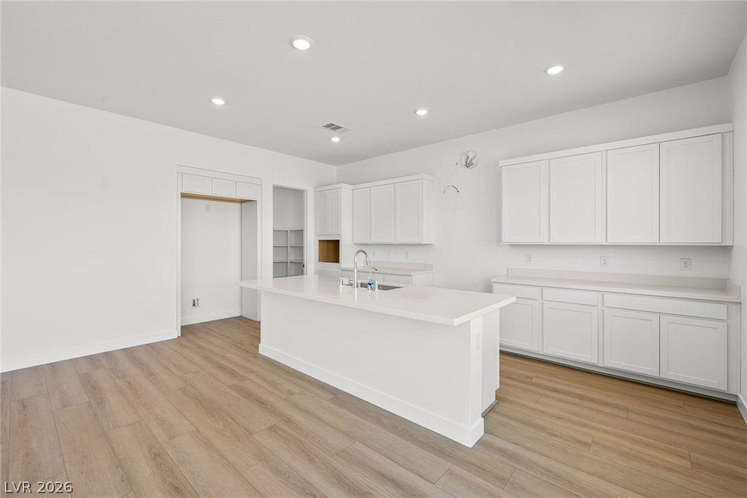 A spacious central island Anchors this modern kitchen finished with clean white cabinetry.