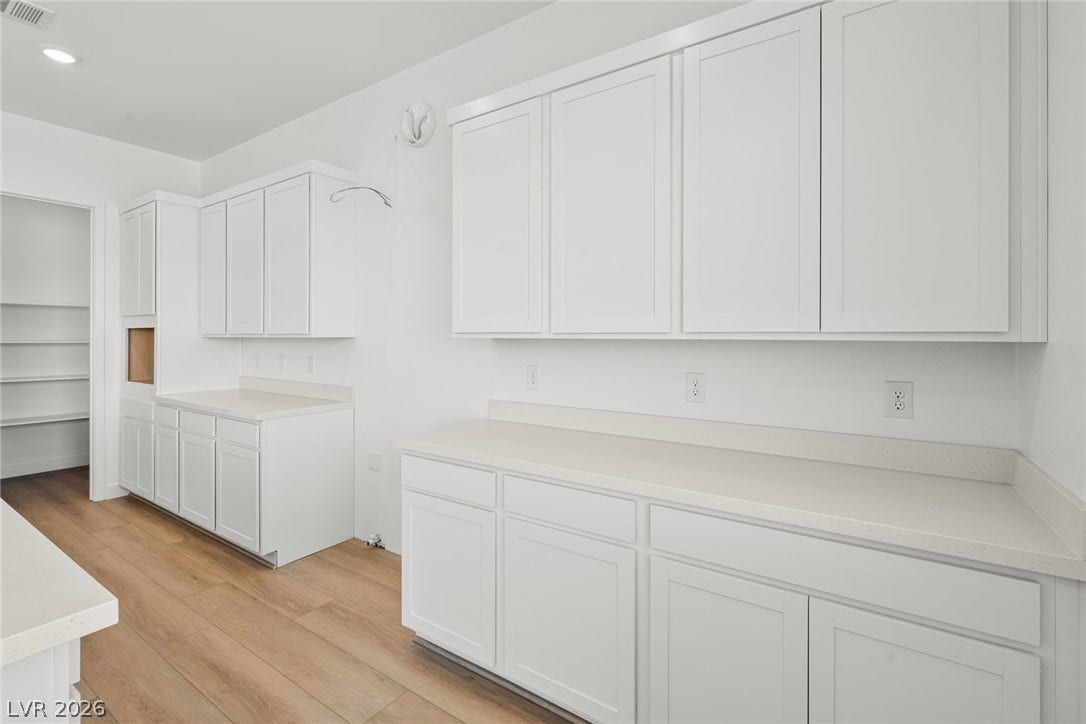 Gleaming stone countertops and abundant shaker cabinetry line this light-filled utility room.