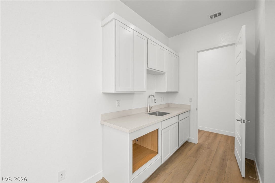 Smooth wood-look flooring and crisp white cabinetry define this functional utility space.