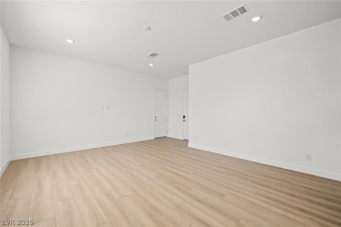Gleaming light wood floors and clean white walls anchor this versatile open living space.