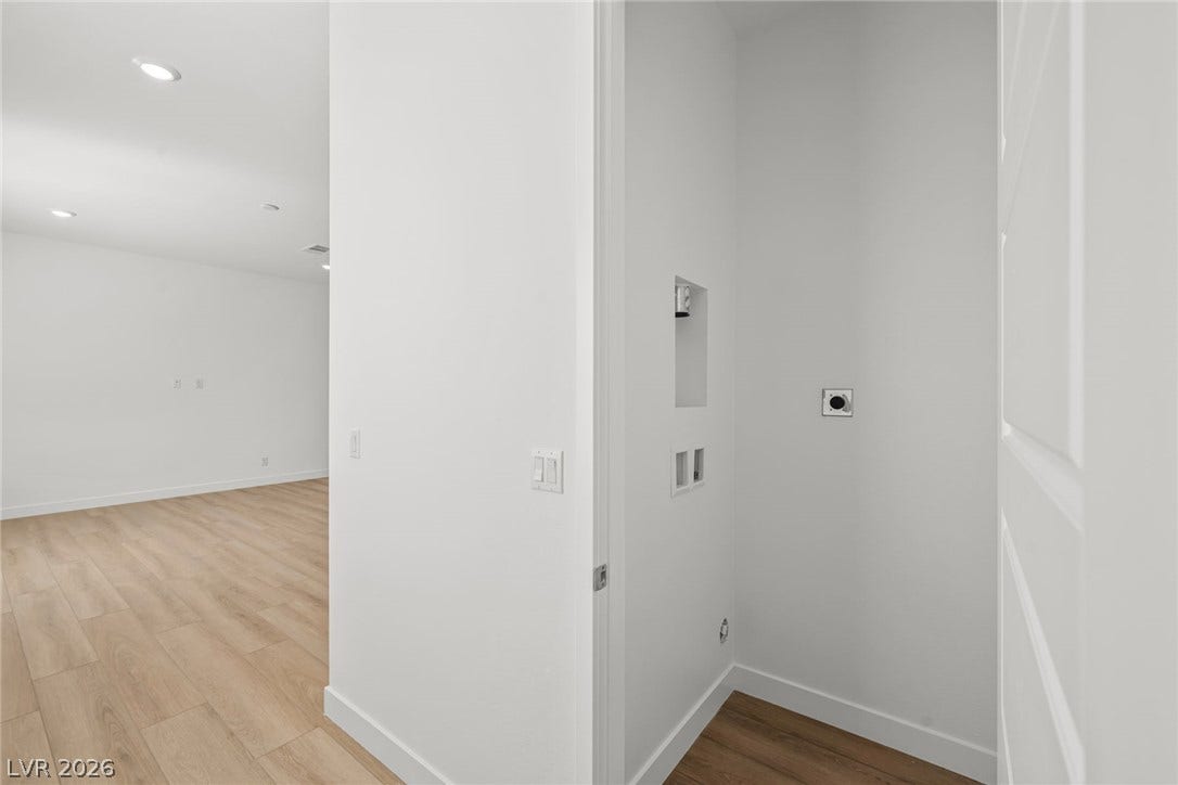 Modern recessed lighting illuminates the sleek wood-style flooring throughout this dedicated utility closet area.
