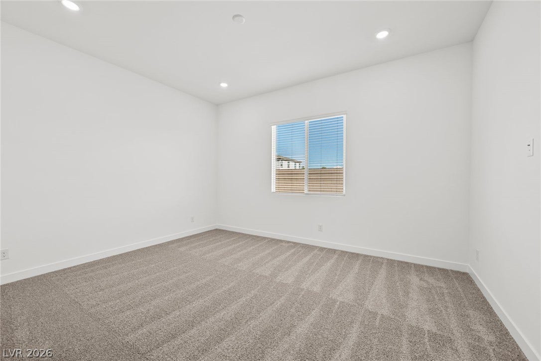 Plush carpeting and modern recessed lighting define this minimalist bedroom space.