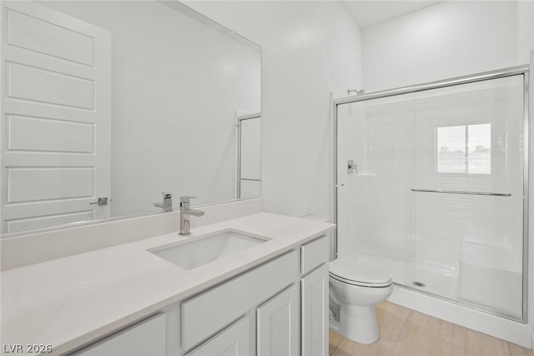 A glass-enclosed walk-in shower highlights this bathroom with a spacious single vanity and tile flooring.