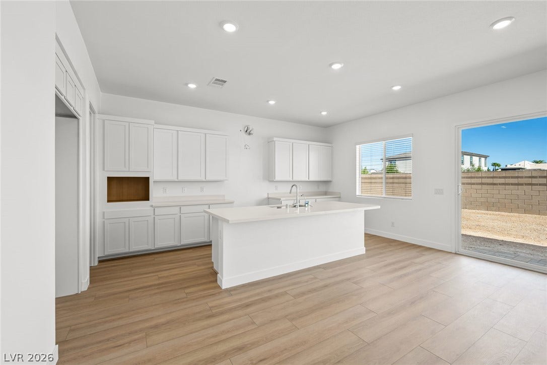 Recessed lighting and warm wood flooring enhance this modern, open-concept kitchen space.