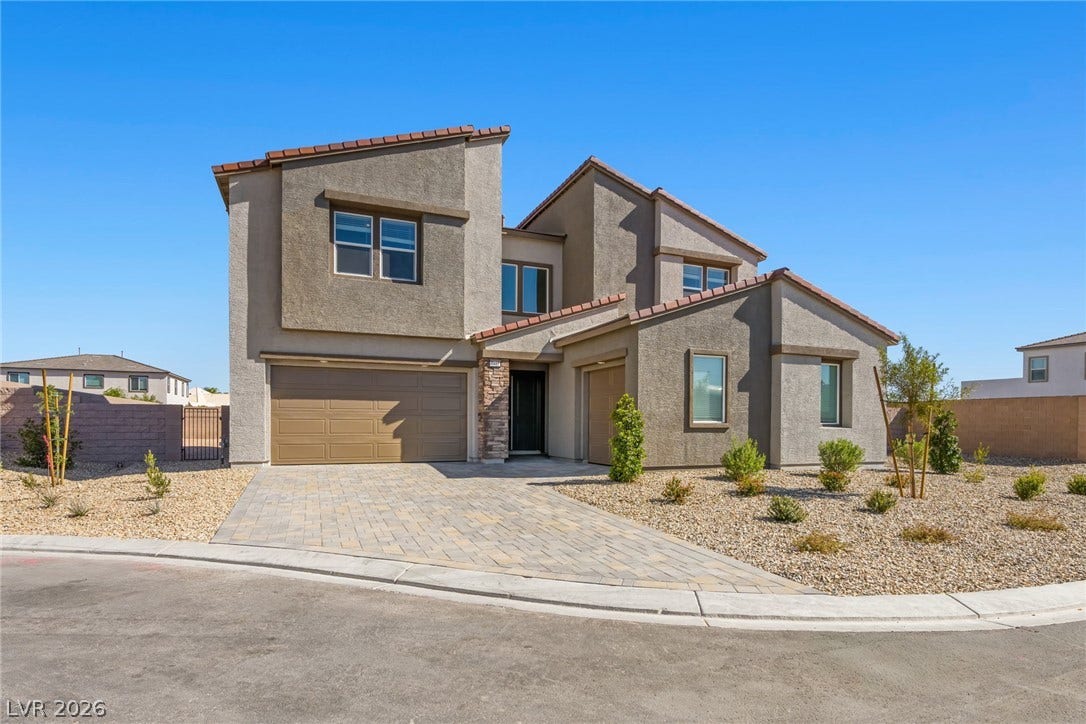A paved driveway leads to the striking stucco exterior of this multi-level home.