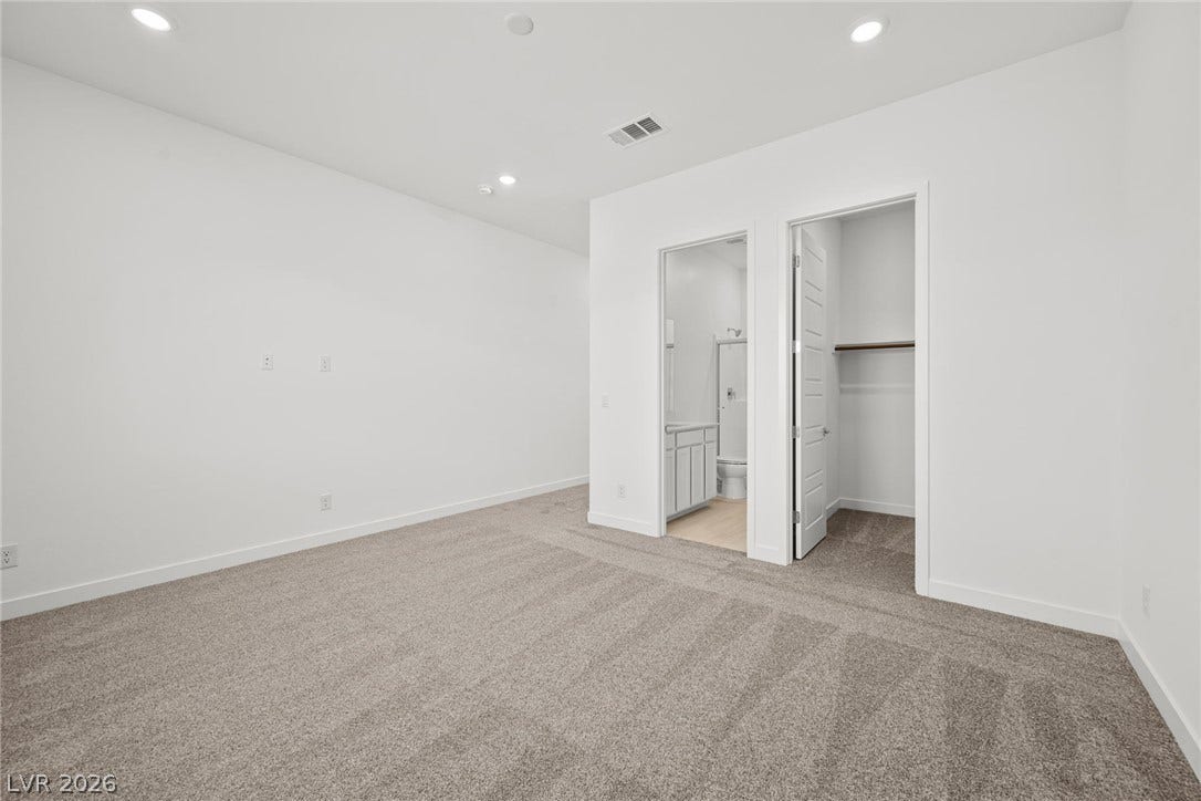 Plush carpeting anchors this spacious bedroom featuring an attached bath and walk-in closet.