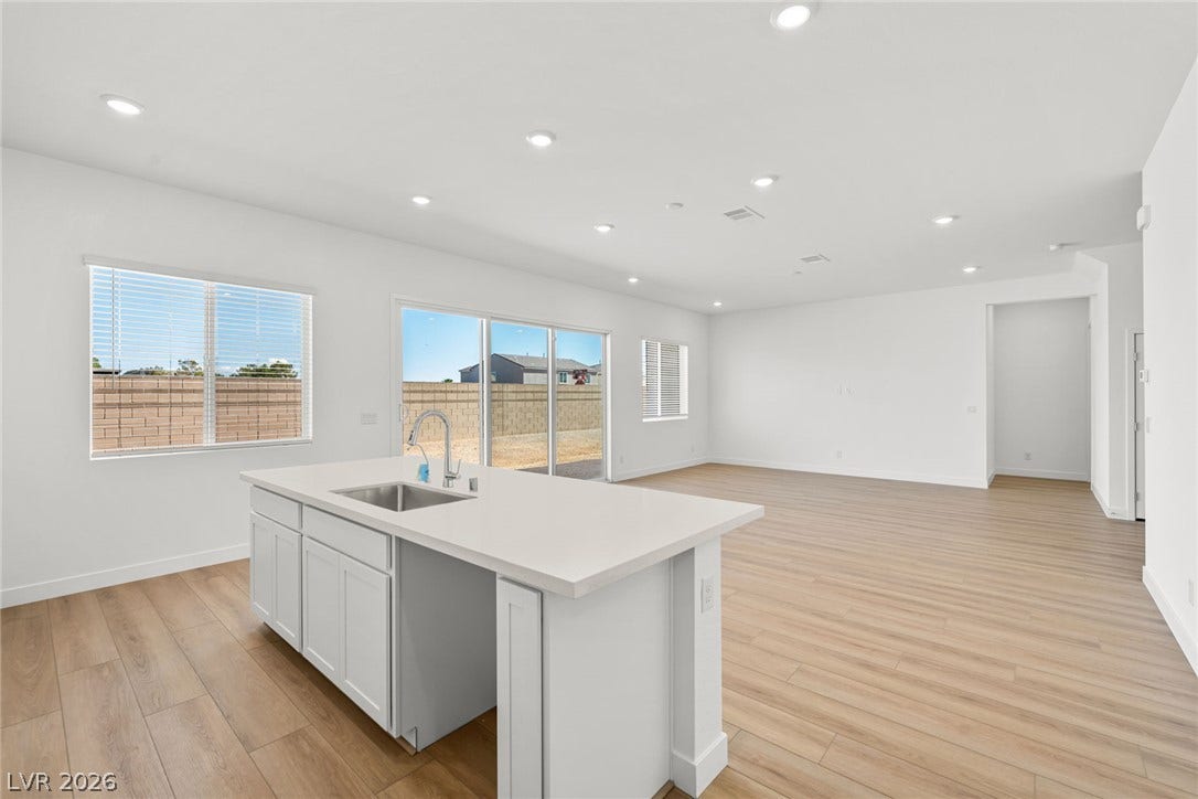 Recessed lighting and warm wood flooring enhance this airy, open-concept living space.