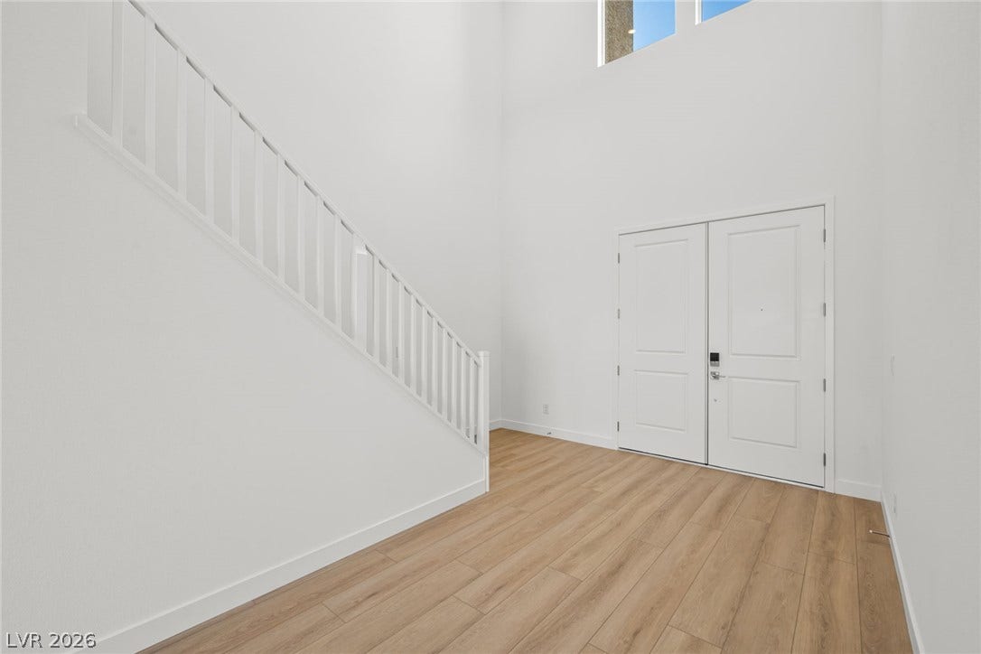 A soaring double-height ceiling and warm wood flooring define this welcoming entryway.