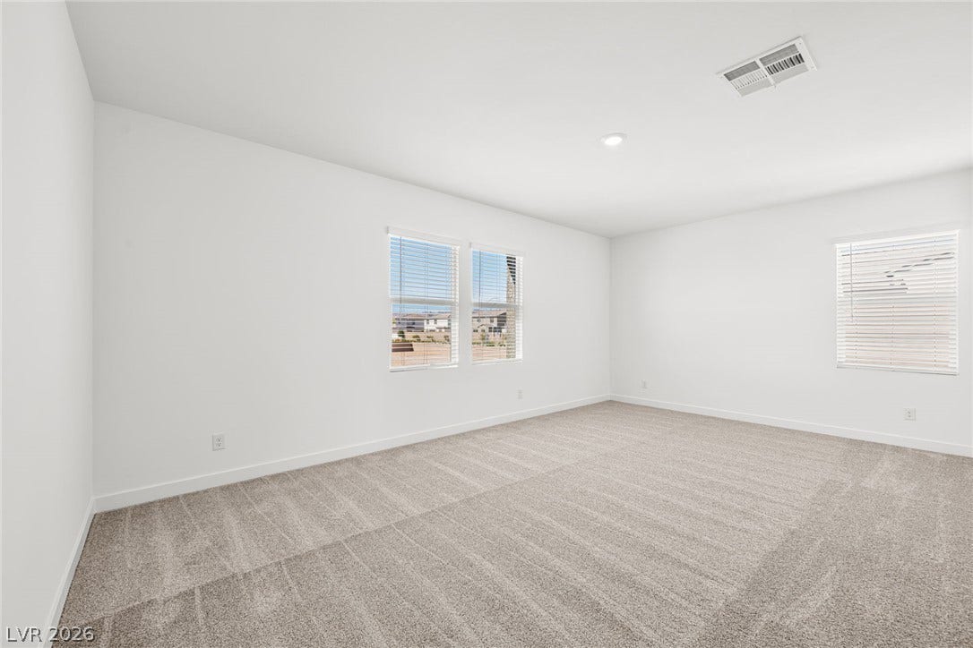 Plentiful natural light fills a versatile living space featuring plush neutral carpeting.