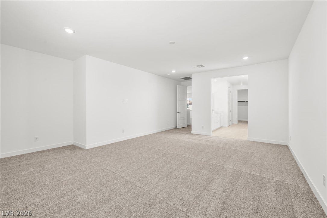 Recessed lighting and plush carpeting define this spacious, modern bedroom suite.
