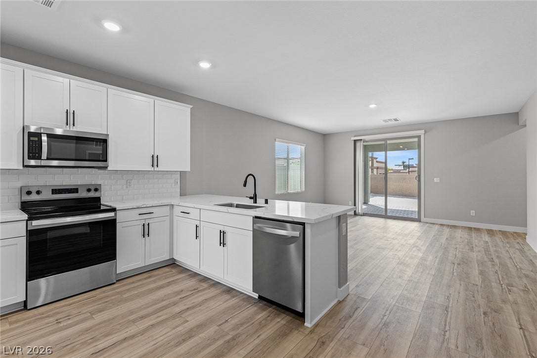4460 Cave Lake Avenue, North Las Vegas, NV 89032 Gleaming wood-look floors unite this modern kitchen and open living space.