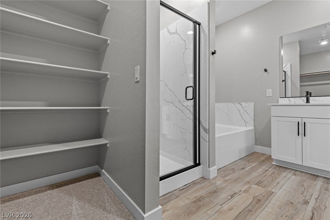4460 Cave Lake Avenue, North Las Vegas, NV 89032 Plank-style flooring complements the modern vanity, glass-enclosed shower, and built-in closet shelving.