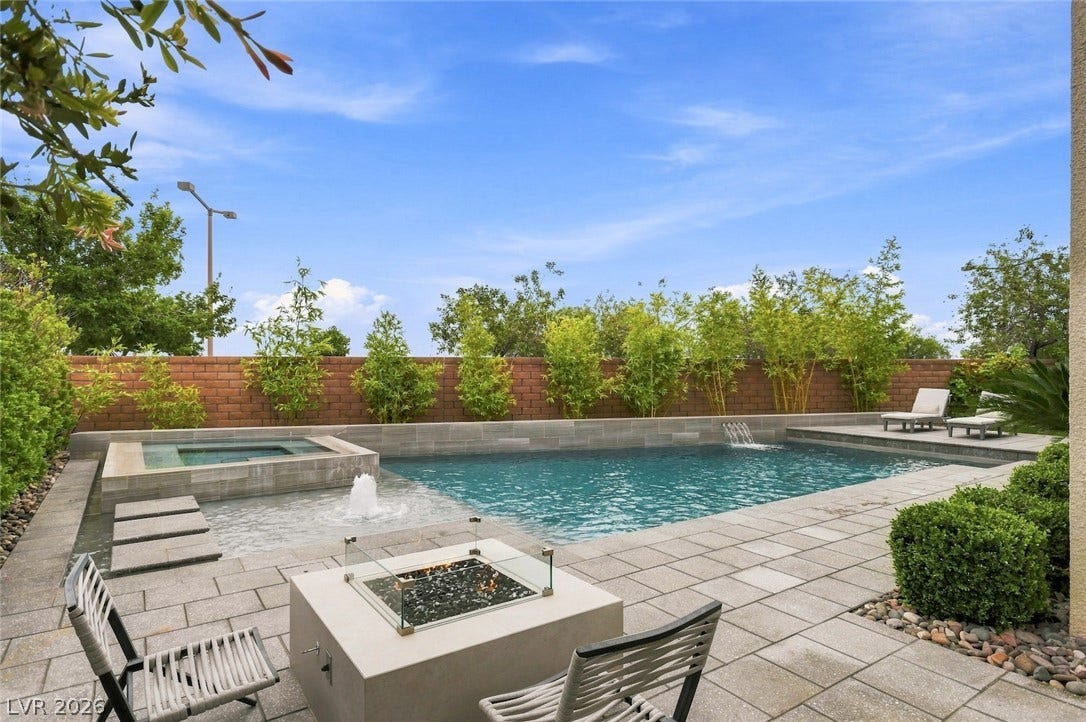 1 Moonfire Drive, Las Vegas, NV 89135 A modern poolscape with stone pavers integrates a built-in spa, waterfall feature, and cozy fire pit.