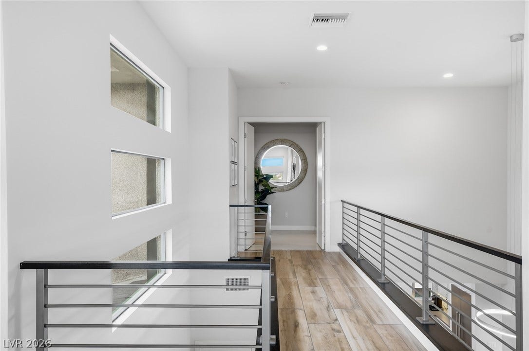 1 Moonfire Drive, Las Vegas, NV 89135 A modern upper-level hallway features sleek metal railings and warm wood-look flooring.