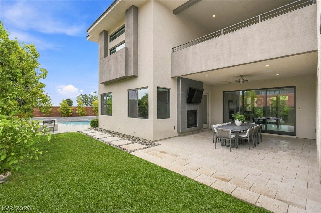 1 Moonfire Drive, Las Vegas, NV 89135 An inviting stone patio overlooks a manicured green lawn and backyard pool.