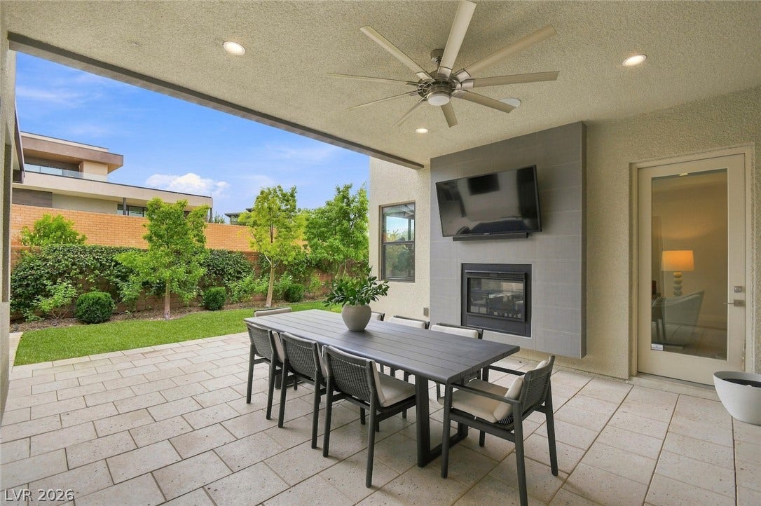 1 Moonfire Drive, Las Vegas, NV 89135 A sheltered dining patio looks out over a manicured lawn framed by mature privacy hedges.