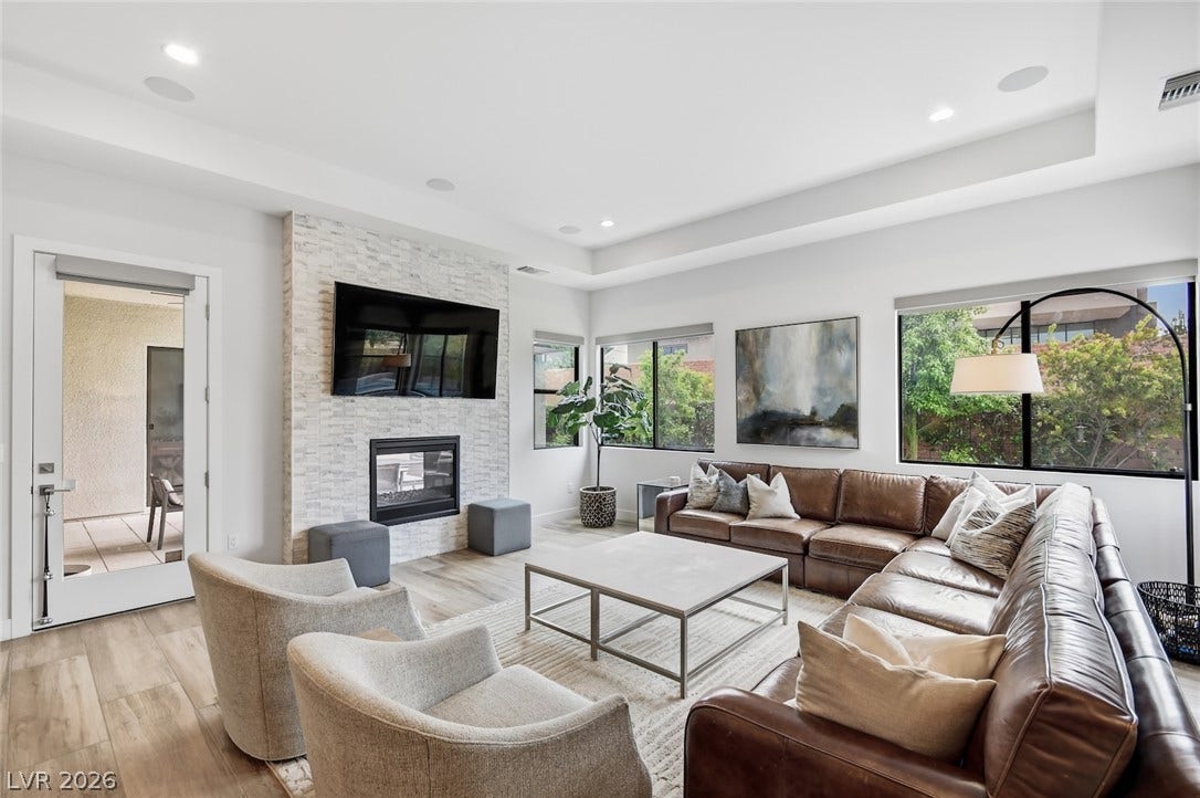 1 Moonfire Drive, Las Vegas, NV 89135 Polished tile flooring and a stacked stone fireplace anchor this light-filled modern living area.