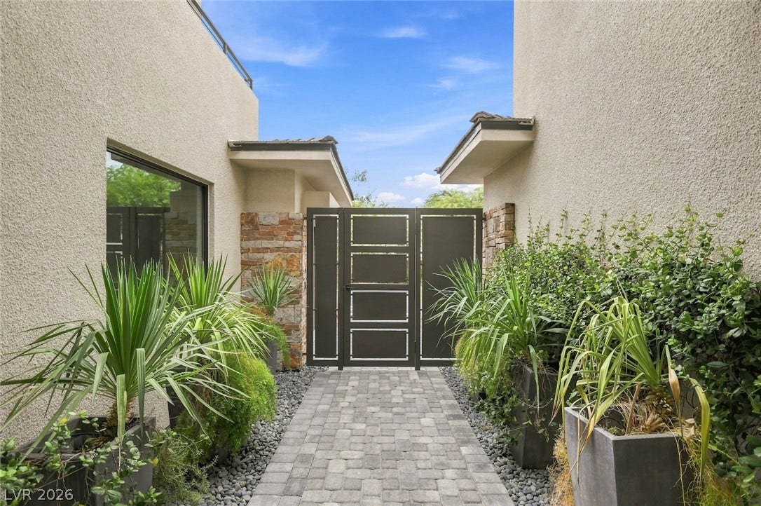 1 Moonfire Drive, Las Vegas, NV 89135 Lush plantings and stone details flank the gated entry path of this contemporary home.