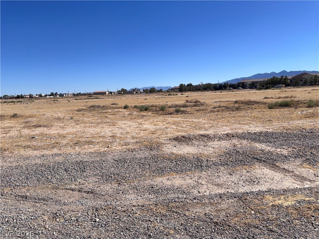 941 E Enchanted Mesa Street, Pahrump, NV 89048 A spacious vacant lot offers sweeping mountain views under a clear blue sky.