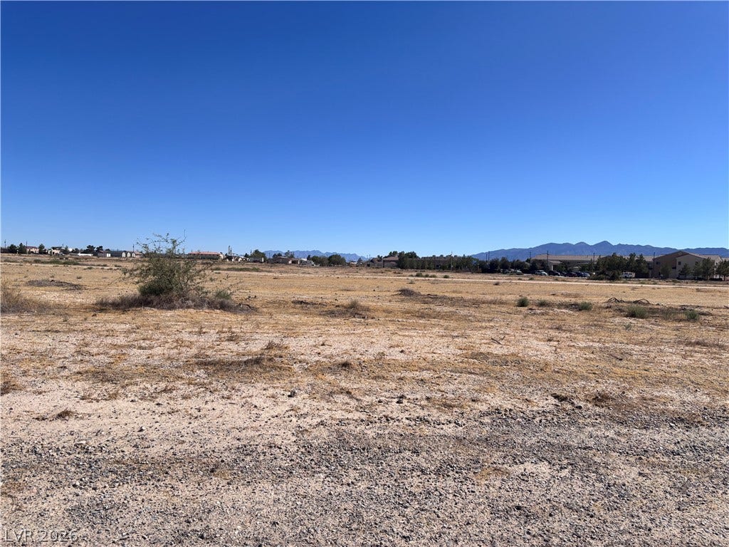 941 E Enchanted Mesa Street, Pahrump, NV 89048 An open desert landscape offers sweeping views of distant mountain ranges under clear blue skies.
