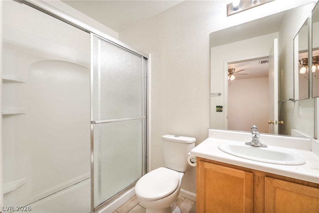 769 Salt Flats Circle, Henderson, NV 89011 Functional bathroom design features a glass-enclosed shower alongside a wooden vanity cabinet.