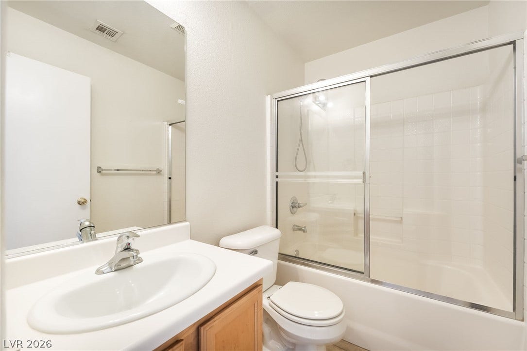 769 Salt Flats Circle, Henderson, NV 89011 Functional bathroom layout features a glass-enclosed tub shower combination and classic wood cabinetry.