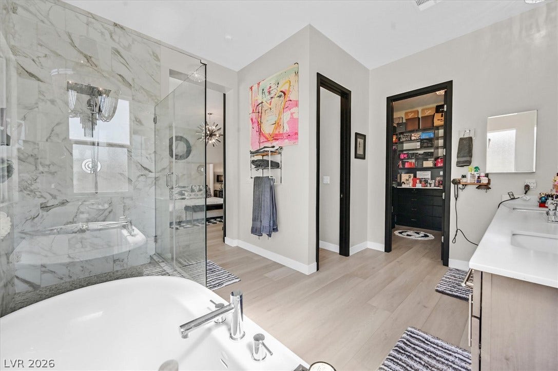2689 Pioneer Estates Court, Las Vegas, NV 89117 A freestanding tub and marble-patterned walk-in shower anchor this primary bath suite.
