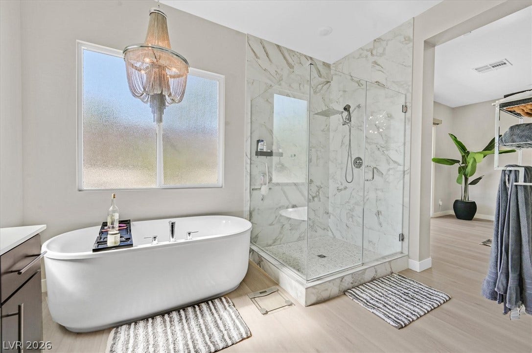 2689 Pioneer Estates Court, Las Vegas, NV 89117 Elegant freestanding soaking tub and glass-enclosed walk-in shower highlight this modern primary bathroom.