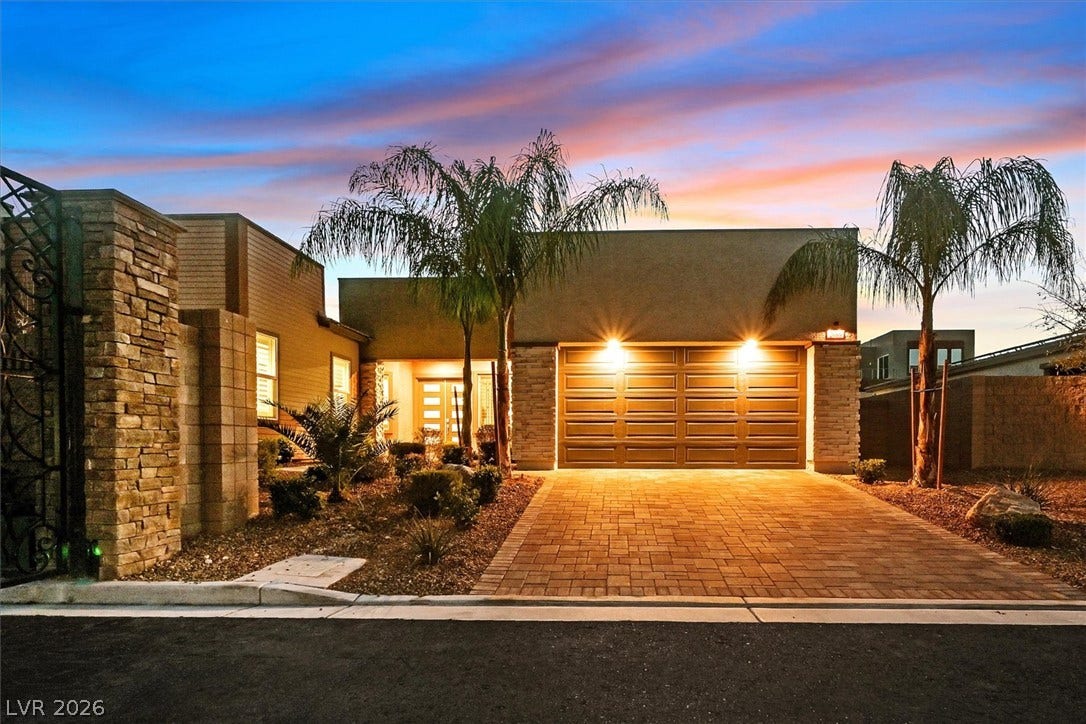 2689 Pioneer Estates Court, Las Vegas, NV 89117 Warm exterior lighting accents the stone-detailed facade and paved driveway of this modern desert residence.