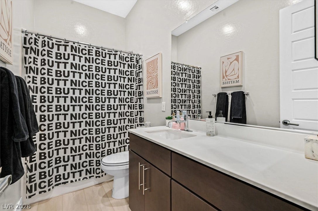 2689 Pioneer Estates Court, Las Vegas, NV 89117 A modern bathroom showcases clean lines alongside a dark vanity and light stone counters.