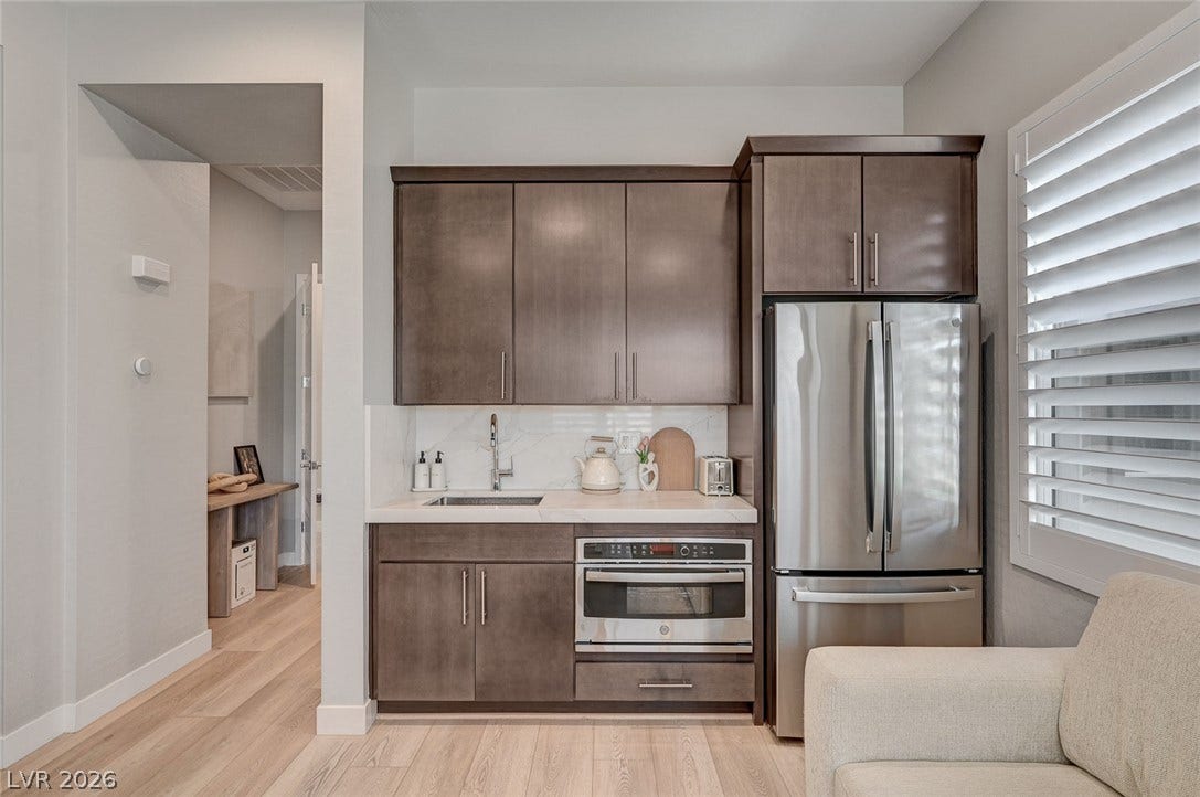 2689 Pioneer Estates Court, Las Vegas, NV 89117 Rich wood cabinetry and integrated appliances define this sleek kitchenette space.